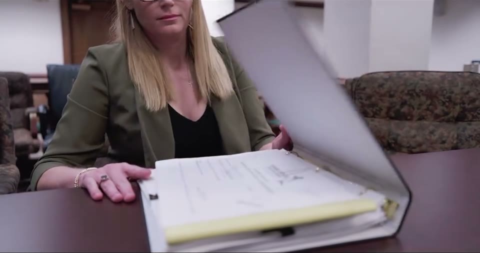 Colleen reviewing a case file in a courtroom