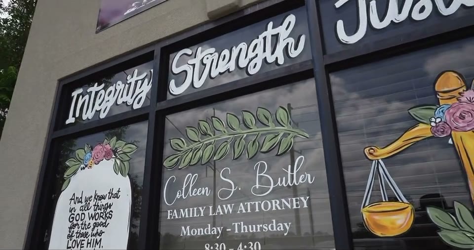 Colleen’s office window in West Monroe, hand-lettered with “Integrity” and “Strength”, an olive branch and scales of justice